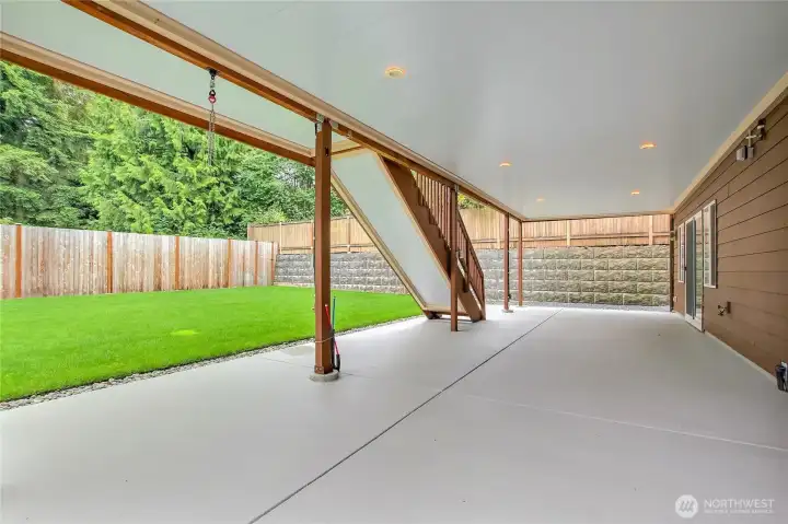 Covered lower concrete patio with stairs leading to main level deck. Sliding doors to the right to access lower level living room. Underdecking gutter system and lighting installed. Covered lower concrete patio with stairs leading to main level deck. Sliding doors to the right to access lower level living room. Underdecking gutter system and lighting installed.