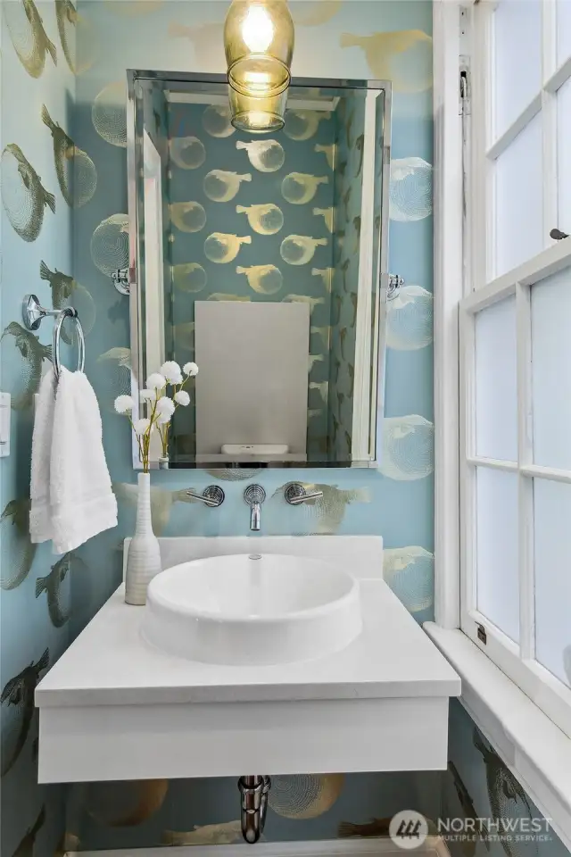 A jewel box of whimsy and refinement, the powder room delights with hand-painted wallpaper and elegant brass accents. Framed by a tall window and historic millwork, even the simplest rituals feel touched by grace.