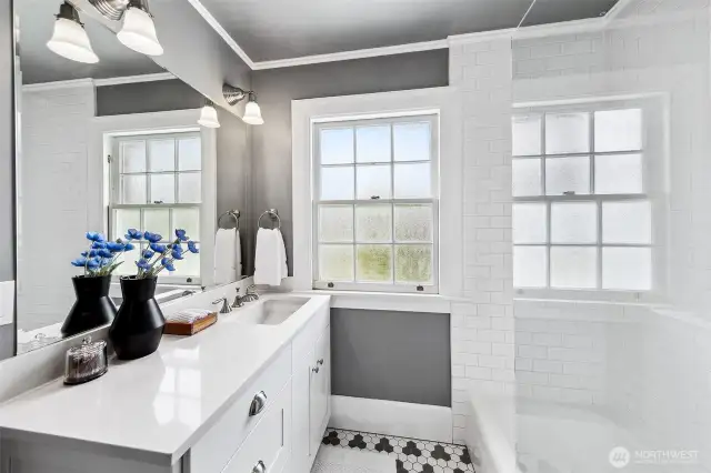 A crisp interplay of light and shadow animates this beautifully restored bath, where checkerboard tile nods to the home's 1930s origins. Awash in natural light, the space offers a daily ritual of renewal—framed by Discovery Park’s ever-changing skies.