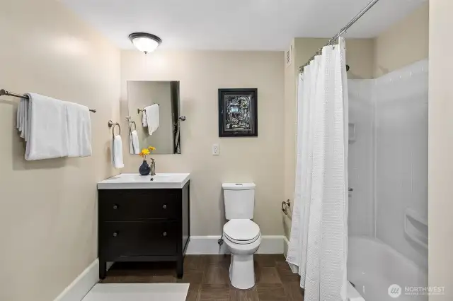 This spacious lower-level bath combines classic simplicity with modern convenience, featuring a full-sized washer and dryer discreetly tucked nearby. Ideal for guest use or daily living, it supports the home’s flexible layout while honoring its enduring sense of calm and care.