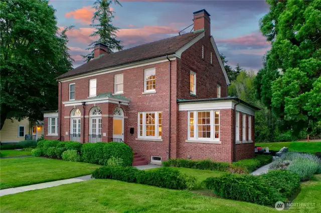 As twilight paints the sky in soft rose and lavender, the home glows from within—its enduring brickwork and classic lines speaking to nearly a century of thoughtful shelter. This is not just a residence, but a rare chapter in Seattle’s living history, where each sunset reminds you: you are home, inside a park, surrounded by legacy.