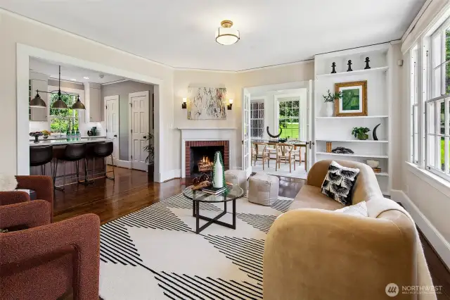 Gracefully proportioned and bathed in natural light, the living room centers around a classic wood-burning fireplace—its mantle a quiet witness to generations of warmth and welcome. This is a space for conversation, contemplation, and connection, where the park beyond the windows shapes the mood within.