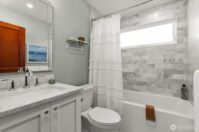 Tastefully remodeled main floor bathroom with quartz countertops, and soaking tub with tiled surround