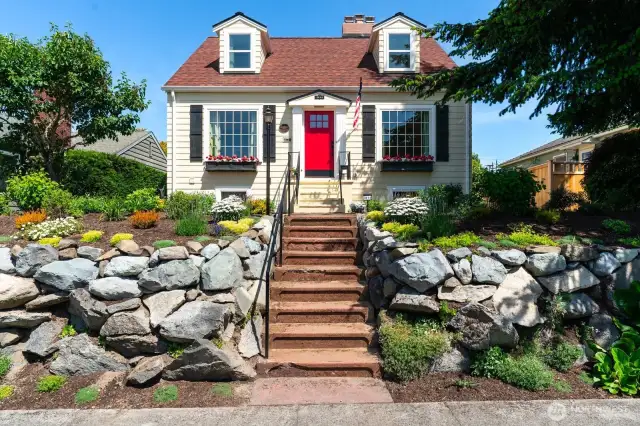 Charming front porch, flower beds and large windows with shutters create and impressive approach
