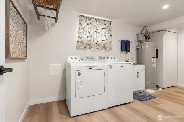 A laundry room with pizzazz, offering plenty of space for a freezer or second brand new washer and dryer, built in ironing board and built in collapsible folding table