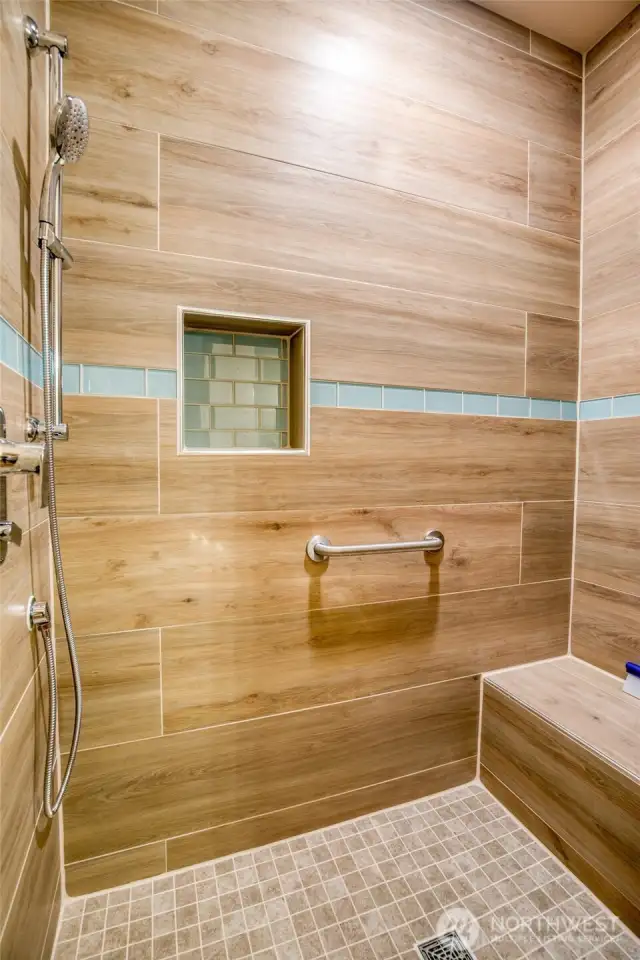 Stunning custom tile work with bench seat in the primary shower.