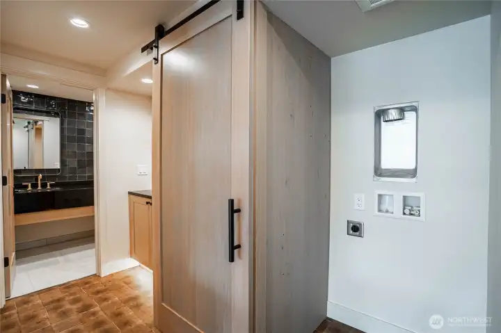 Laundry area for stacking washer/dryer are concealed with a barn door in the hallway to the guest bathroom.