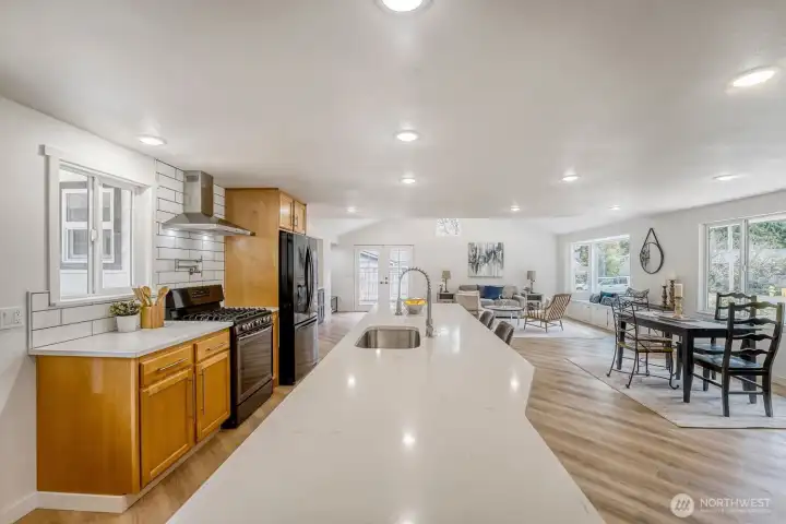 This light-filled kitchen boasts a bright, open layout designed for both everyday living and effortless entertaining. A striking 12-foot quartz island with ample seating anchors the space, offering the perfect spot for gathering and prep. The chef’s area features a premium cooktop enhanced by a convenient pot filler above the stove, adding both function and luxury.