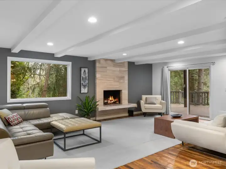 This expansive open-concept living room defines luxury with the ceiling and designer exposed beams creating an inviting atmosphere. The sliding doors offer a seamless indoor-outdoor flow to your private oversized deck overlooking Carkeek Park.