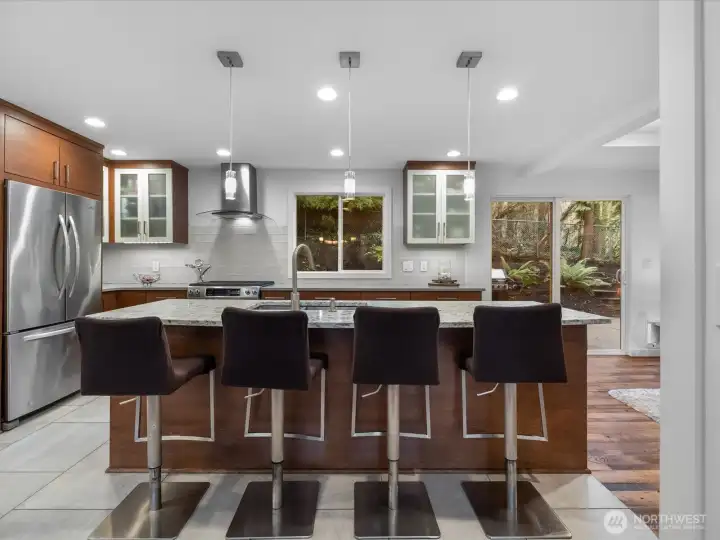 View of the gourmet open-concept kitchen from the dining room, complete with breakfast bar - all flowing seamlessly into your private wooded backyard.