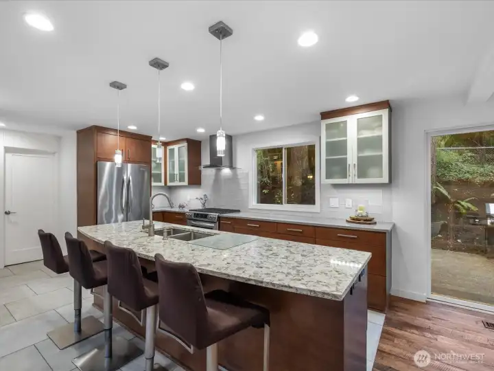 Gourmet kitchen features high-end finishes, including sleek quartz countertops, stainless-steel appliances, and custom soft-close drawers paired with elegant recessed and pendant lighting.
