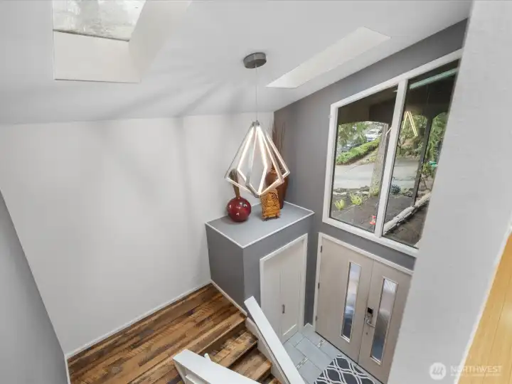 Experience the ultimate in modern sophistication with this sun-drenched, two-story foyer featuring a designer geometric pendant; notice the skylights flooding the foyer with natural light, creating a bright, airy atmosphere that instantly elevates the home's entrance.