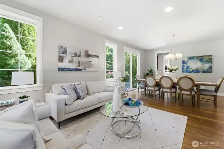Formal living and dining spaces glow with natural light, soaring 11-ft ceilings, and warm hardwood floors