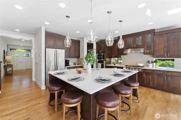 Gather around the grand island with seating for six and warm pendant lighting. Stainless-steel appliances stay, and the coffee bar and low windows frame peaceful garden views