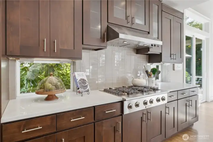 A 6-burner gas cooktop anchors this workspace, with the full run of cabinetry below featuring generous pull-out drawers perfect for storing pots, pans, and larger kitchen essentials