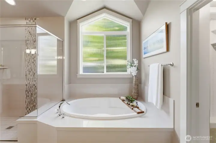 A beautiful tub framed by an oversized window that pours natural light into the room