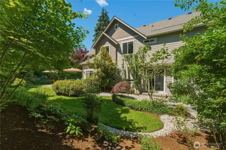 From the garden, enjoy a south view toward the patio off the formal dining room, surrounded by two apple trees, a fig tree, and a plum tree. To the right, the wisteria-draped arbor and garden gate complete this charming corner of the yard