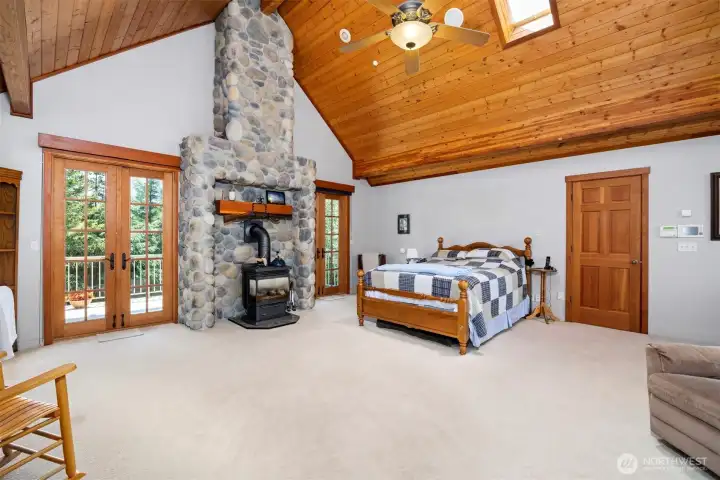 The primary suite is very spacious and has a gas freestanding stove. There is a private deck with French doors that overlooks the large lawn. The closed door leads to one of the 2 large walk-in closets.