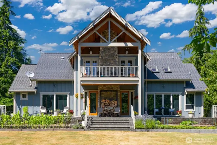 The rear elevation of the home has the large patio surrounding the home as well as the deck off the primary ensuite.