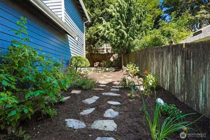 Side yard has stone path flanked by garden beds. Side yard has stone path flanked by garden beds.