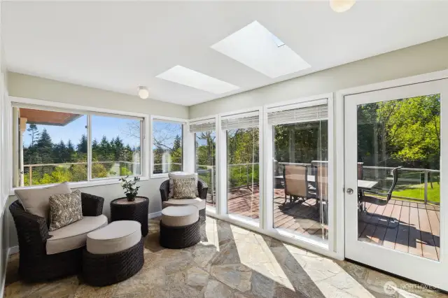 This bright Sunroom has all new Milgard Ultra windows. It leads out to a wraparound deck and the Koi ponds to the right. There's a Sun Setter electric awning mounted above those full-length windows.