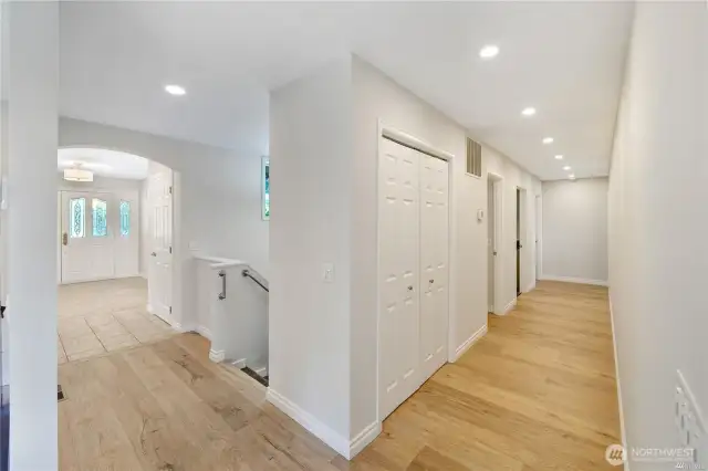 Here you can see the new imported, wide plank flooring with underfloor heating.  The first door on the left is the guest bathroom.  The second door on the left is the Utility room.  The third and last door on the left is the home office.  The Primary bedroom and bath are both located at the end of the hall on the right.