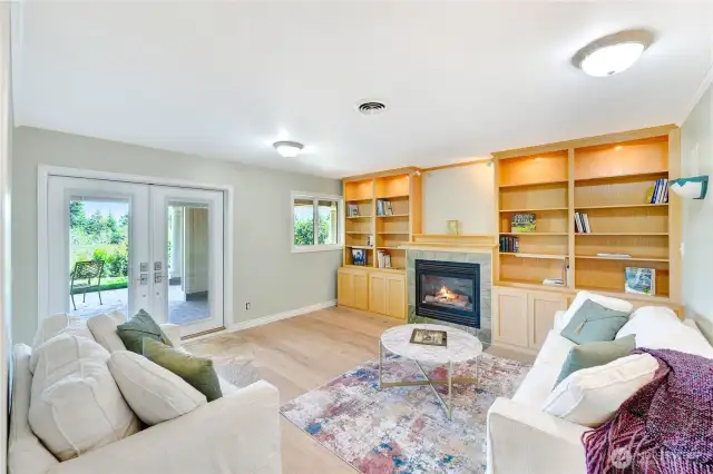 Comfortable library with custom built-in shelves, gas fireplace, and new European wide-plank flooring.  The new French doors lead to a covered patio overlooking the pastures and mountain views.