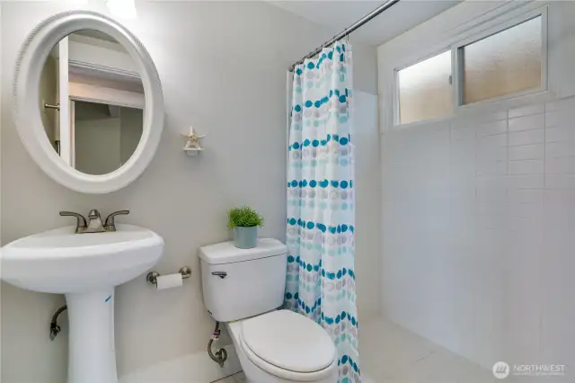 Featuring fresh paint, a spacious walk-in shower, stylish tile floors, and a classic pedestal sink, this bathroom combines functionality with timeless charm.