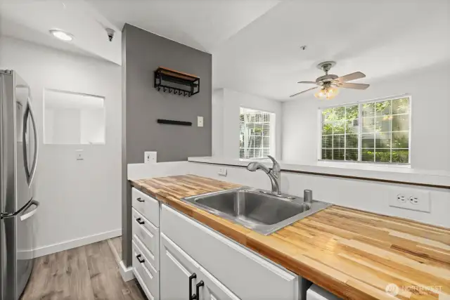 Charming kitchen featuring butcher block counters, a brand-new range, and a stainless steel refrigerator—combining warmth and functionality in one inviting space.