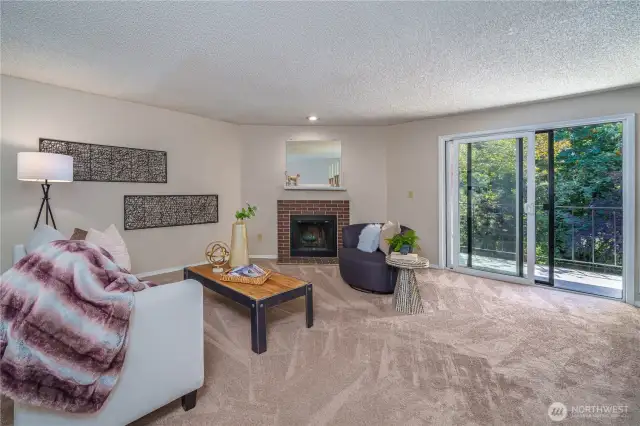 The spacious living room features a cozy wood-burning fireplace and oversized sliders that bring nature indoors.