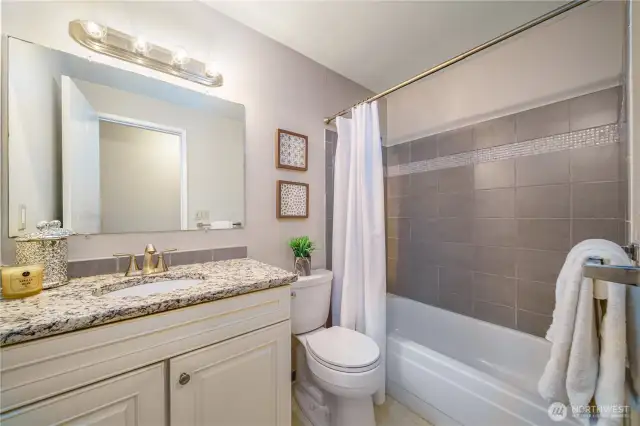 Across the hall, the full guest bath also includes granite counters and updated finishes.