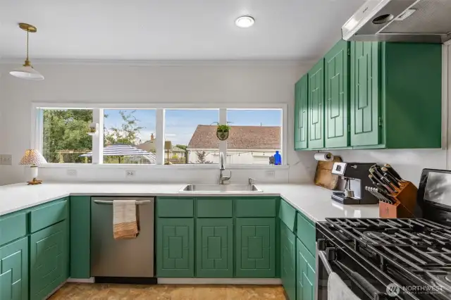 Natural light pours through windows into kitchen overlooking backyard
