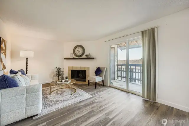 Bright and airy living room featuring fresh paint, stylish laminate hardwood floors, and a cozy wood-burning fireplace.