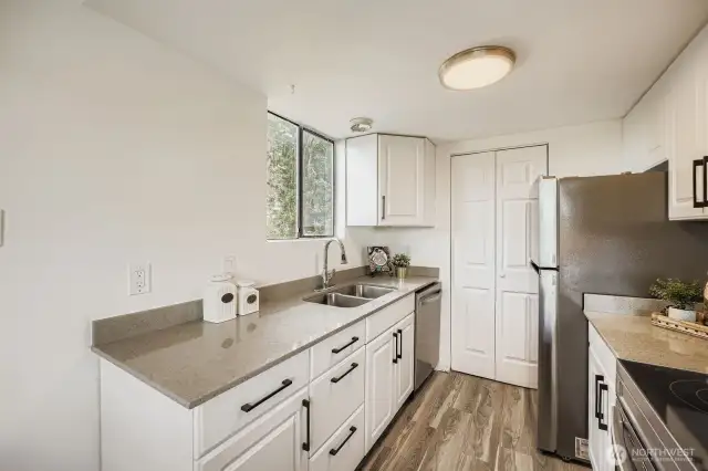 Beautifully updated kitchen featuring newer cabinets, sleek quartz countertops, an under-mounted sink, brand new appliances, and a spacious pantry for added storage.