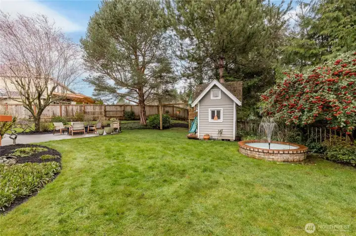 Level fully-fenced yard includes beautiful mature landscaping and a serene fountain