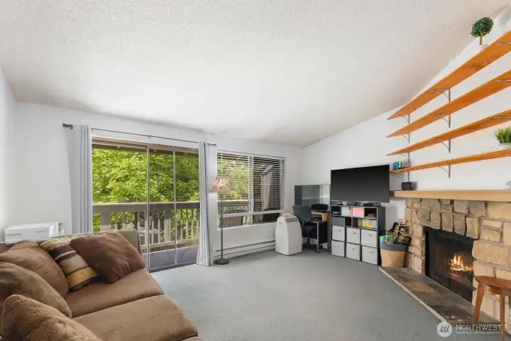 Light-filled living room with large windows, sliding glass door access to the deck, and peaceful tree-lined views.