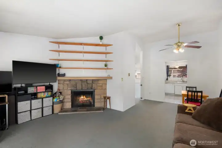 Comfortable living space with wood shelving details, fireplace focal point, and room for relaxing or work-from-home flexibility.