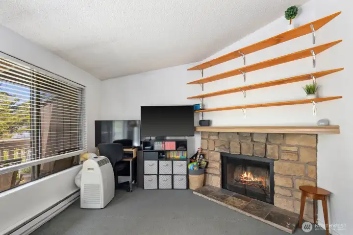 Stone fireplace with surrounding built-in shelving creates a cozy focal point in the main living area.