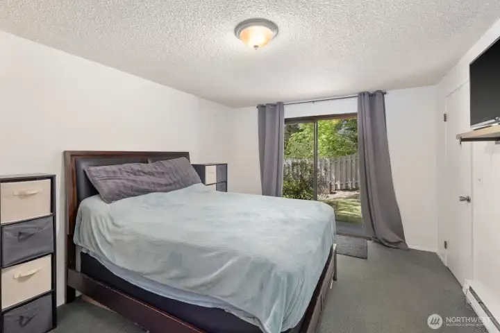 Spacious bedroom with sliding glass door access and views of the fenced outdoor area.