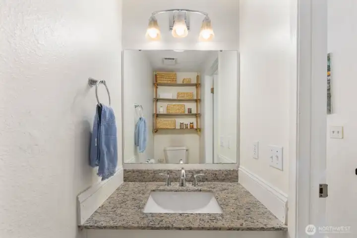 Additional bathroom space with updated countertop and extra storage shelving.