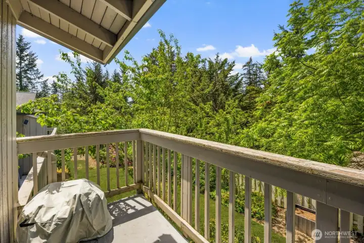 Private balcony surrounded by mature trees and greenery.
