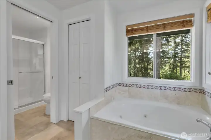 Primary bathroom looking into the separate shower and toilet area and linen closet