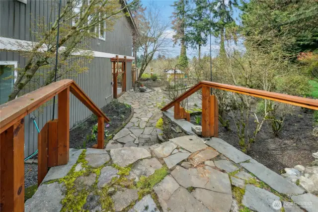 Stone patio extends around the side, fanning out into a lovely open air space. Well-established blueberry bushes yield lots of fruit!