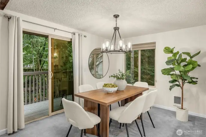 Spacious dining room with updated chandelier, deck access, and wooded views.