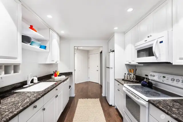 The kitchen has engineered hardwood floors, granite counters, and plenty of cabinets for storage.