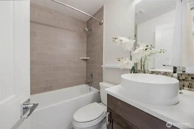 Beautiful and sleek design full bath on the main floor with custom tile work bath surround, flooring, backsplash and quartz counters.