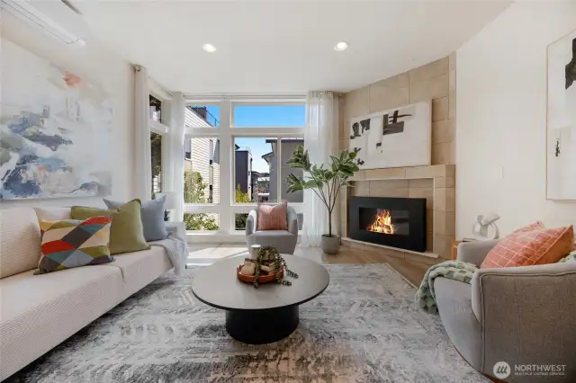 Main living room area with wall of windows, custom ceramic tiled surround & tiled mantle gas fireplace, and true oak hardwood floors.