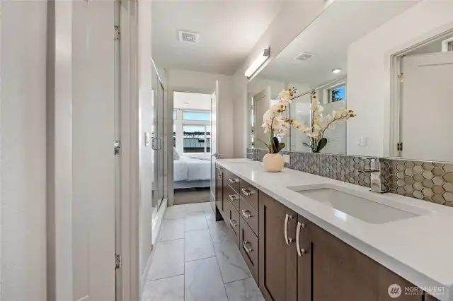 Awesome primary bath double recessed vanity with wide counter space, lots of cabinets, custom tiled flooring and backsplash, room wide mirror.