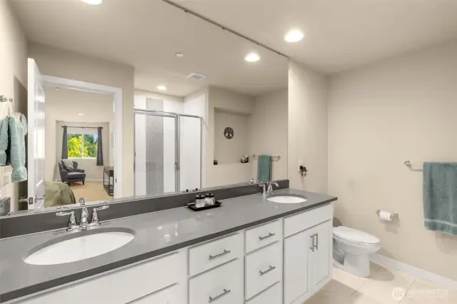 Dual vanity sinks and beautiful tiled shower in the primary suite bath.