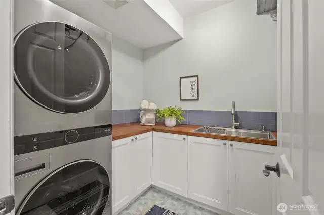 Convenient laundry/mudroom just off the garage with custom cabinetry/wood counters and utility sink.